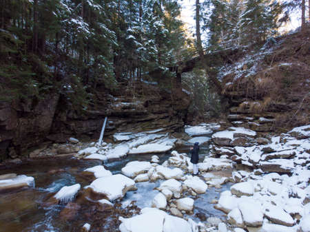 Winter Frozen Stream Flowing Under the Small bridge in Natural Stone Arch in Deep Valley. Carpathians Mountains, Ukraineの写真素材