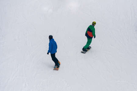 Two Snowboarders riding on White Snow Covered Slope top viewの写真素材