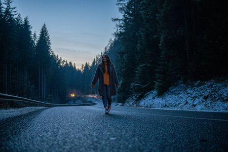 Beautiful Young Woman On the Dark Forest Road at Winter. Twilights, Car Lights on Backgroundの写真素材