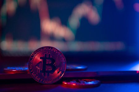 Bitcoin Coins are standing on laptop in neon Light with a Chart on a screen at backgroundの写真素材