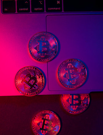 The coins of Bitcoin are on the laptop Surface. Purple and pink neon lightの写真素材