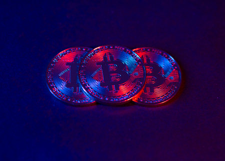 The coins of Bitcoin are on a dark Surface. Purple and pink neon lightの写真素材