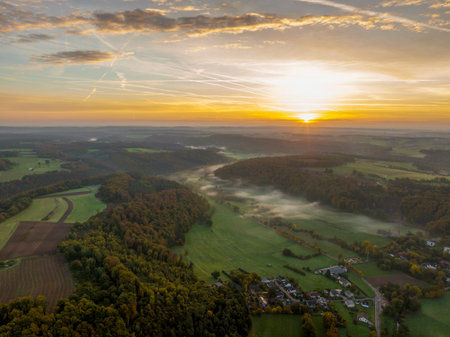 Aerial drone Sunrise view Above autumn colored forest and Valleys in Luxembourg, covered in morning fogの写真素材