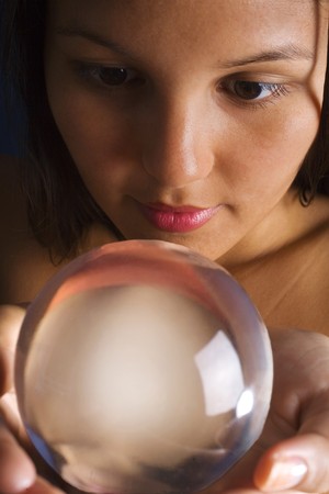 A young Asian woman looks into a crystal ballの写真素材