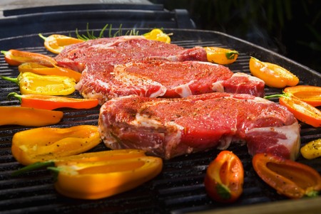 ribeye steaks cook on the bar-b-que grill with baby bell peppersの写真素材