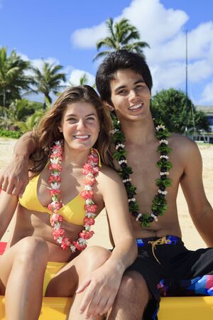 young woman with an island man on the beach in hawaii wearing leiの写真素材