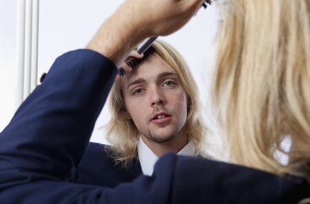 young man brushes his hair in a mirrorの写真素材