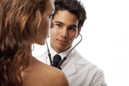 young asian doctor listening to the heartbeat of a female patient with his stethoscopeの写真素材