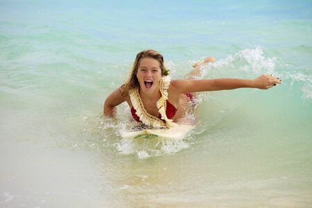 teenage girl in the ocean with her surfboard at kailua beach