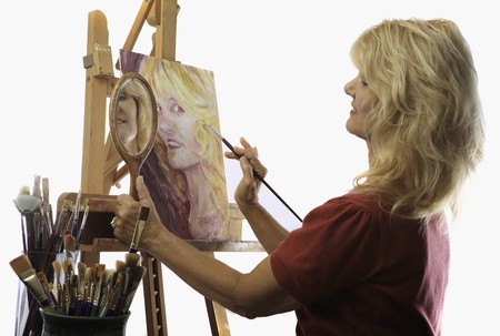 female artist in her fifties paints self portraitの写真素材