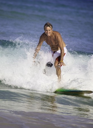 sixty-four year old man surfing in hawaiiの写真素材