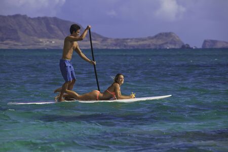 couple on standup paddle board in hawaii