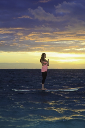 woman doing yoga on her paddle board at sunriseの写真素材