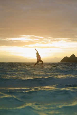 woman doing yoga on her paddle board at sunriseの写真素材