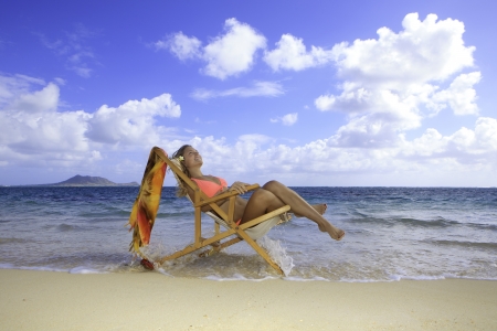 blond in bikini on a beach chair by the oceanの写真素材