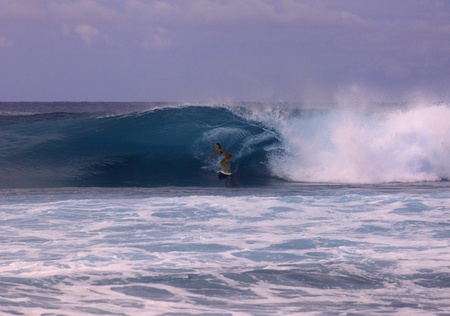 young woman on surfboard riding a big wave in hawaii