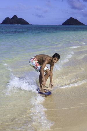 polynesian boy riding his skim board in Hawaii