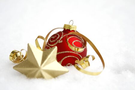 Red-golden bauble with the ribbon on the snowの写真素材