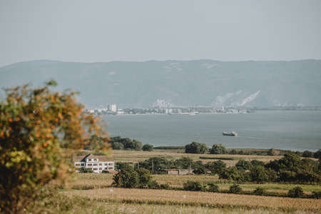 The scenery with big cargo ship is incoming to the industry harbour on the Danube river on the serbia romanian border with hills of Serbia in background during the sunny summer dayの写真素材