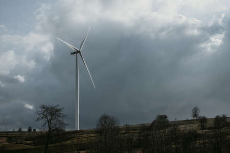 One wind turbine for renewable wind energy on horizon under the cloudy sky during the spring day on hills of Romania. Copy spaceの写真素材
