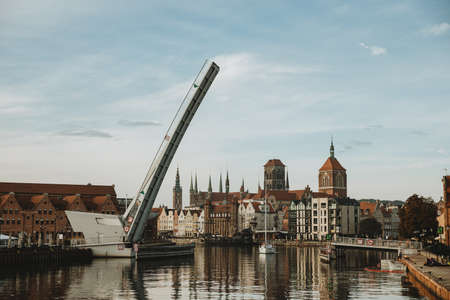 opened bridge above the MotÅawa river with a passing yacht and historical center of gdansk in the backgroundの写真素材