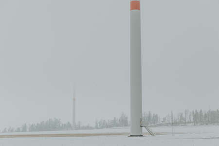 Base of a wind turbine mast with stairs to entrance on the windmill farm in winter foggy landscapeの写真素材