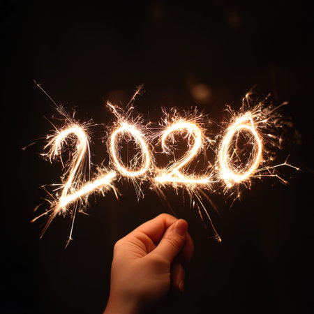 New year written with sparklers and hand on a black background