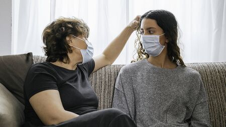 Mother and daughter protected by a mask against coronavirus, covid-19 or any other disease, sitting...