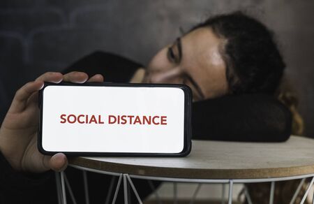 Social distance. Young woman resting while holding a mobile phone with a blank screen to put a text...