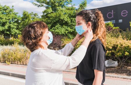 New normal. Mother and daughter protecting themselves against the coronavirus. Mother puts her...