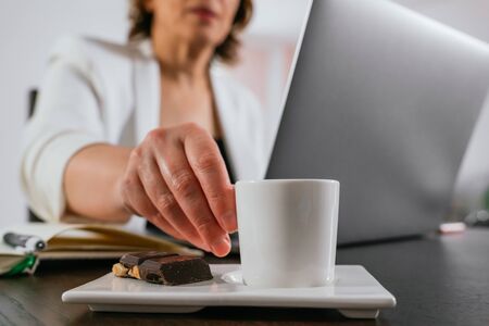 Businesswoman having coffee while she works. Senior woman working from home. Having a coffee. Coffee...