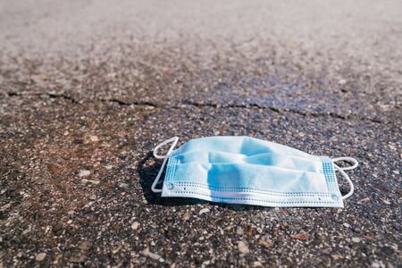 Discarded mask. Surgical mask used on the floor. Protective mask in the trash. Surgical mask on floor. Face mask abandoned in the street. People discard surgical protective face maskの写真素材