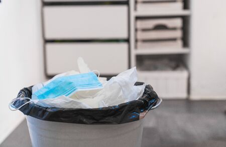 Mask thrown in the trash. Mask discarded. Used surgical mask. Ffp protective mask and plastic gloves in the trash. Surgical mask in trash can. Abandoned face mask. Coronavirus. End of coronavirusの写真素材