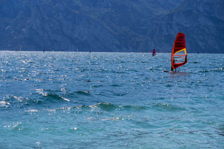 Surfer catching the breeze on the stormy lake Garda Italy with the mountains in the background