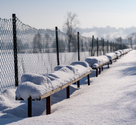 Strewn with snow, benches by an abandoned football fieldの写真素材