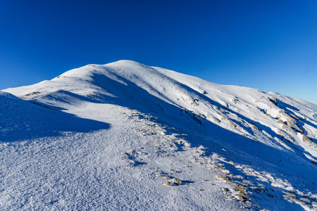 Snow-covered and icy hiking trails in the Polish Tatras with a view of the surrounding high peaks.