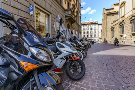 Scooters and motorcycles parked in a perfect row on a street in Italyの写真素材