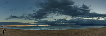 Evening wide view from the beach to the sea with clouds in the background