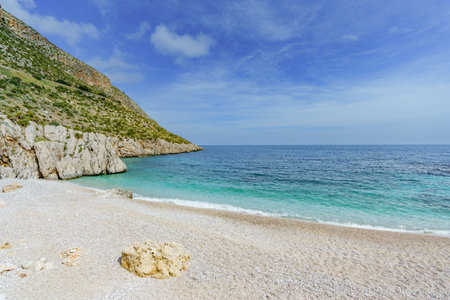 A beautiful view of the calm sea and the sandy beach surrounded by rocksの写真素材