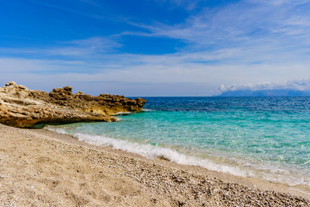 A beautiful view of the calm sea and the sandy beach surrounded by rocksの写真素材