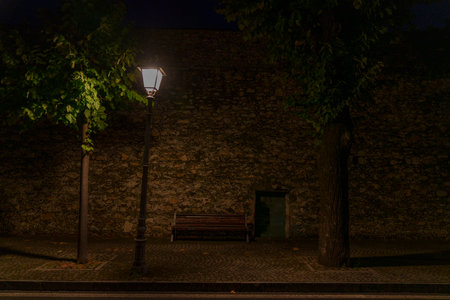 The atmospheric light of a city lamp in a quiet street with an old wall in the backgroundの写真素材
