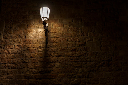 An atmospheric and delicately glowing old lamp, illuminating a brick wall.の写真素材