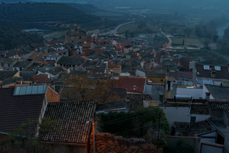 Evening view of the roofs of a small town with atmospheric street lighting and mountains in the backgroundの写真素材