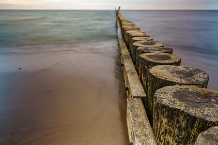 Seaside breakwaters protecting the shore of a beautiful sandy sea with washed-out wavesの写真素材