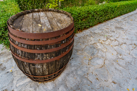 A very old wooden barrel, abandoned on a path in a green park