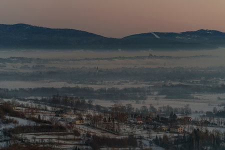 Morning view of a foggy mountain valley with village houses surrounded by smog in winter scenery at sunrise.の写真素材
