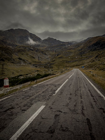 Cracked asphalt of the TransfÄƒgÄƒrÄƒÈ™an climbs through an empty high-altitude pass in the...