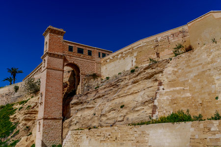 Historic bastions with brick tower and arches crown a rugged escarpment, showing layered stonework and vegetation.の写真素材