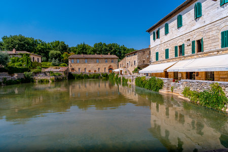 Clear blue sky over historic stone buildings and green shutters in Tuscany, Italy.の写真素材