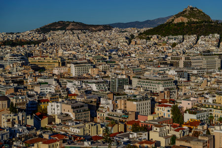 Daytime view of Athens city center with Lycabettus Hill and surrounding mountains under clear sky.の写真素材